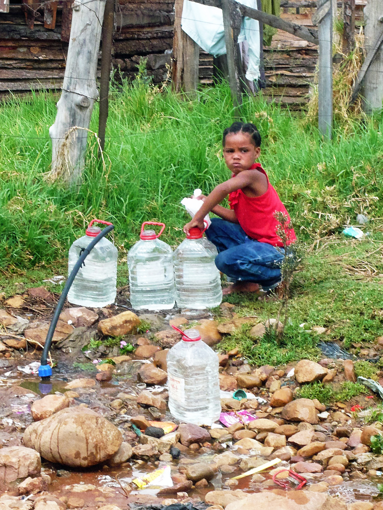 Kind an einer öffentlichen Wasserstelle im Township