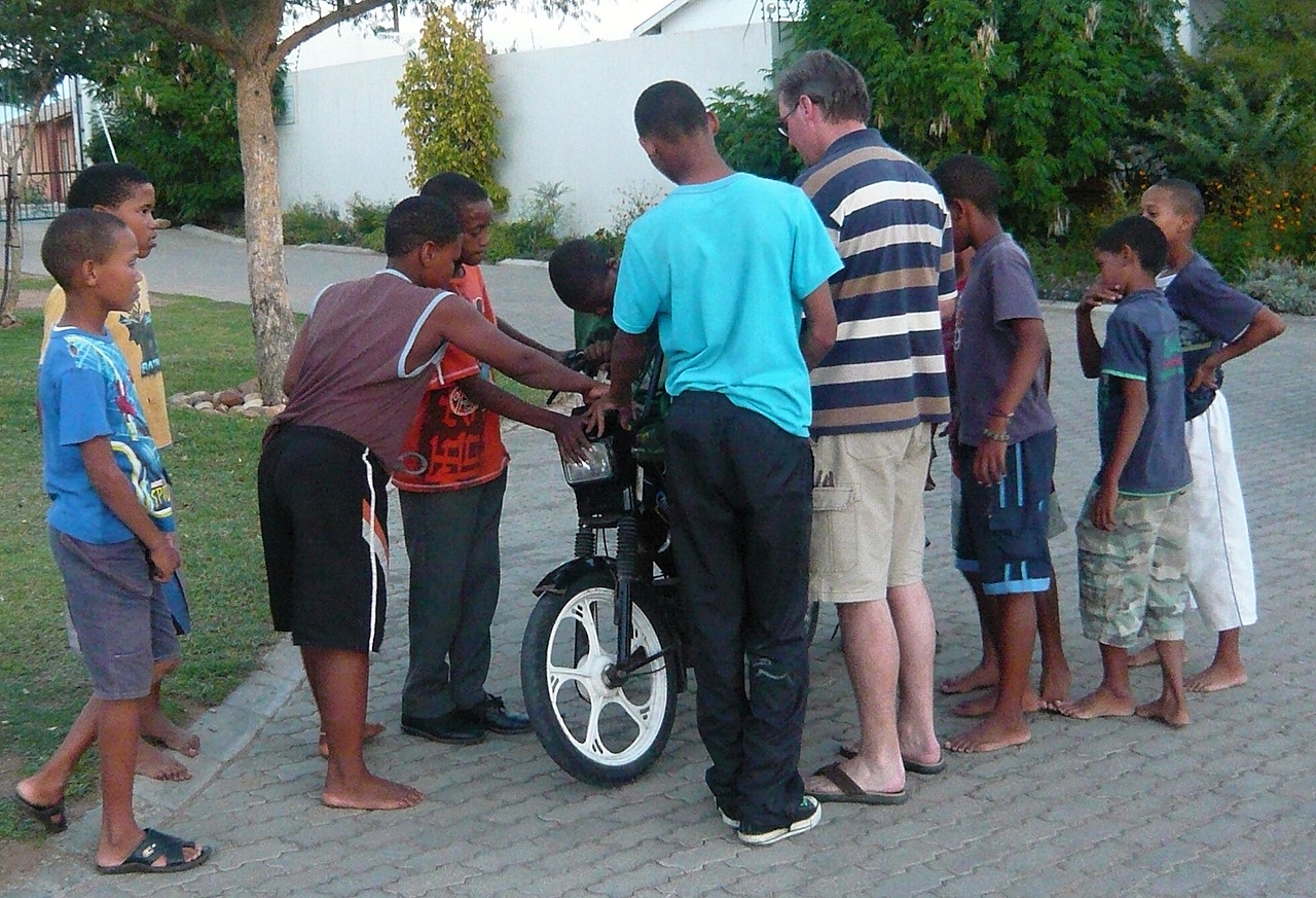 Pater David und die Kids mit einem Motorrad.